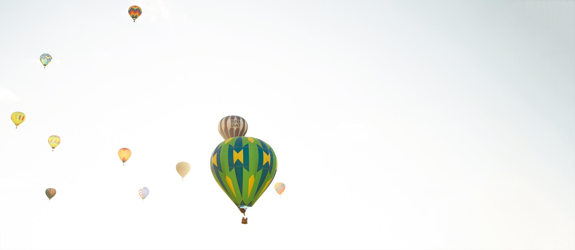 Hot air balloons drifting across a pale sky